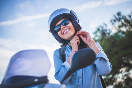 A person putting on a helmet next to a vehicle.